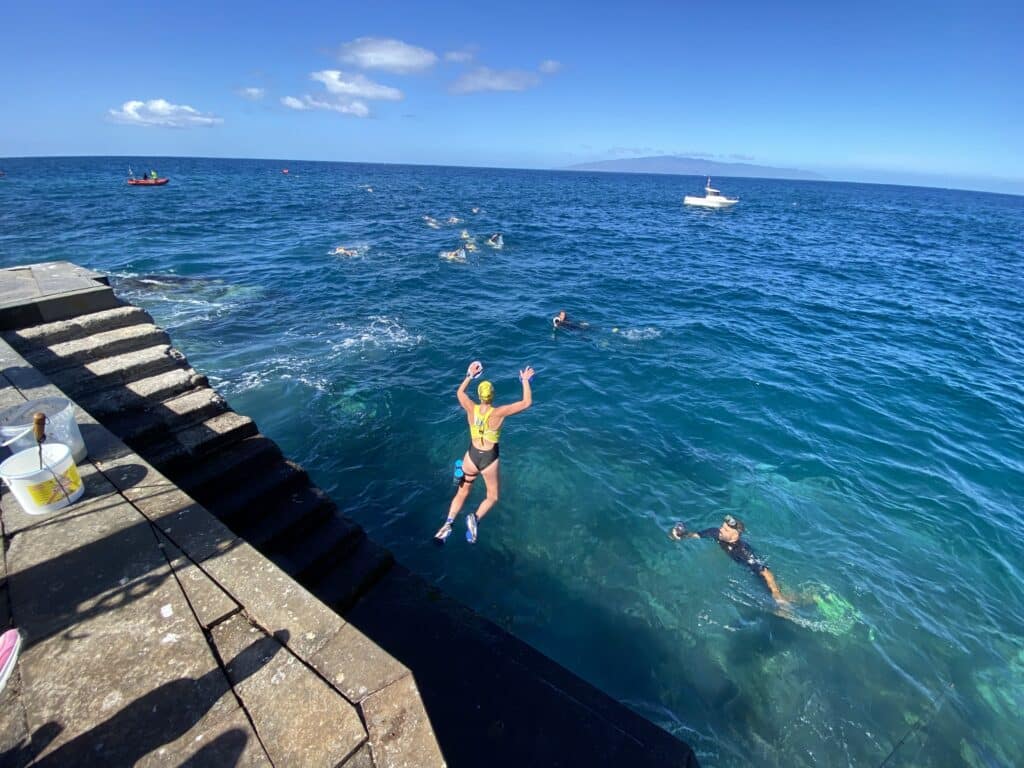 Persona tirandose al agua en la carrera del swimrun de playa de san juan